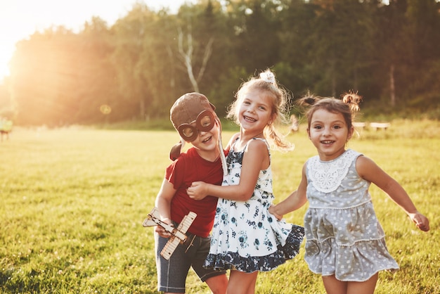 Broer en twee zussen spelen samen. Drie kinderen spelen met een houten vliegtuig buiten