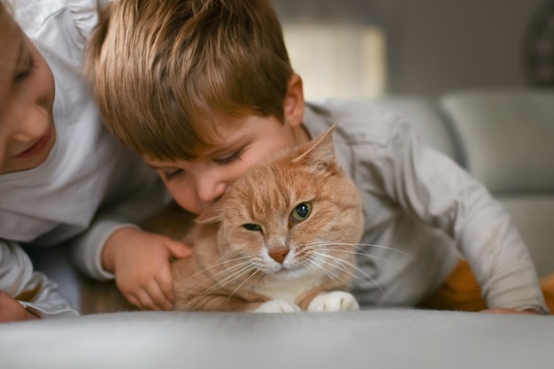 Broer en zus knuffelen een rode kat op de bank