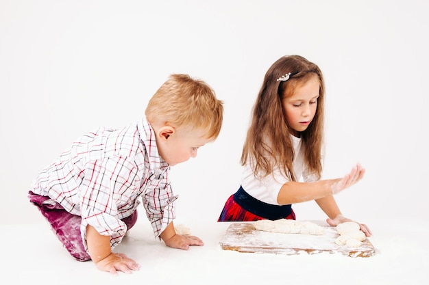 Broer en zus koken bakkerij op keuken Kleine helpers bereiden deeg voor zoete traktatie witte achtergrond