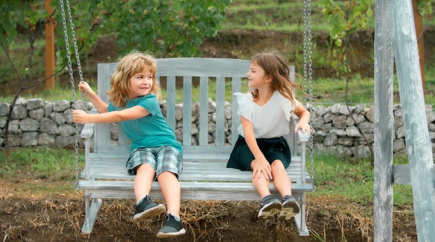 Broer en zus schommelen buiten kleine jongen en meisje werken in de tuin twee gelukkige kinderen in