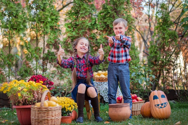 Broer en zus spelen in de herfsttuin, omringd door fruit, groenten en fruit