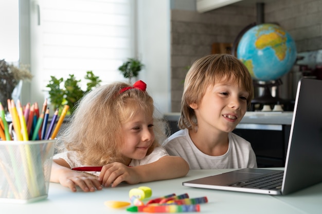 Broer en zus studeren thuis aan laptop kinderen en gadgets