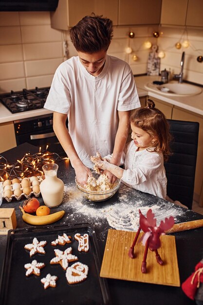 Broer met zijn kleine zusje eten bereiden in de keuken en veel plezier.