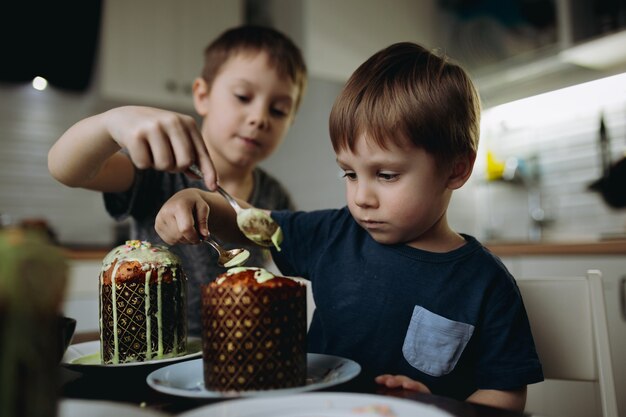 Broers die paascakes versieren met glace icing en sugar topping. Afbeelding met selectieve aandacht. Hoge kwaliteit foto