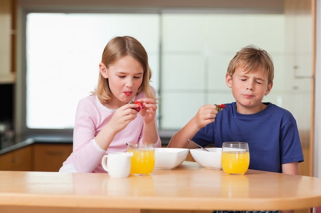 Broers en zussen aardbeien eten voor het ontbijt