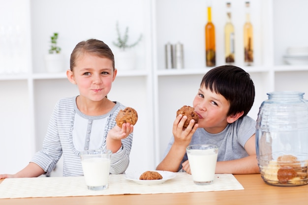 Broers en zussen die koekjes en consumptiemelk eten