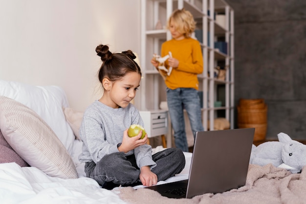 Broers en zussen in bed kijken naar video op laptop