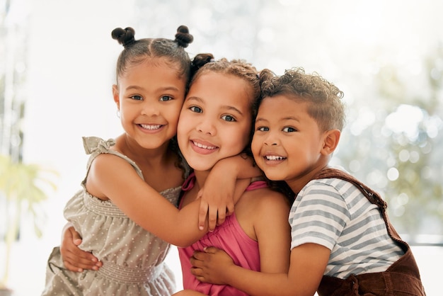 Broers en zussen jongen en meisje kinderen knuffelen en hechten samen als een schattig gelukkig gezin binnenshuis in de zomer Portret van jonge broer en zus kinderen glimlachen omarmen en genieten van hun jeugd