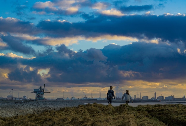 Foto broers en zussen lopen op het veld tegen de hemel bij zonsondergang.