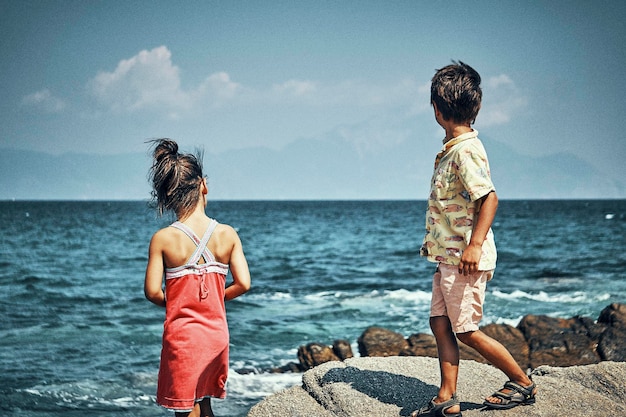 Broers en zussen op het strand tegen de lucht.