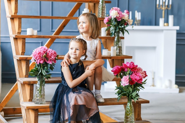Broers en zussen zitten in het midden van bloemen in een vaas op houten trappen thuis