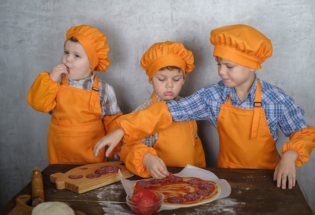 broers helpen moeder om pizza te koken met worst en kaas