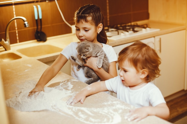 broertje en zusje spelen thuis met meel en een kat