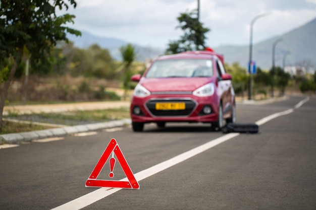 Auto rotta con una ruota di scorta e il segno sullo sfondo delle montagne