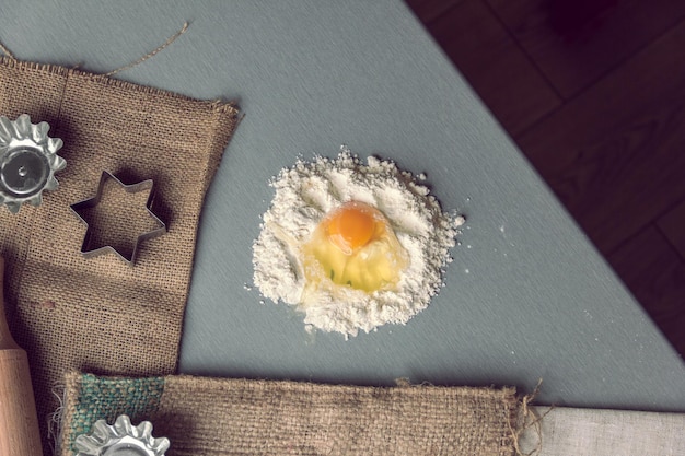 Foto rompere l'uovo di gallina in farina con il mattarello e le forme per la cottura