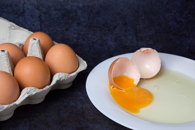 Uovo di gallina rotto in un piatto sull'azzurro