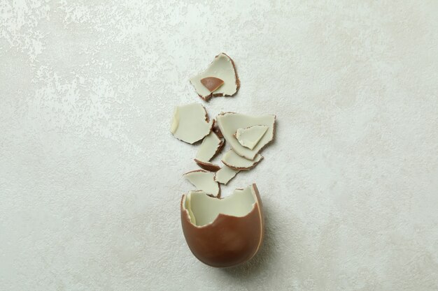 白い織り目加工の壁に壊れたチョコレートの卵