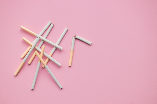 Broken cigarette on a pink background