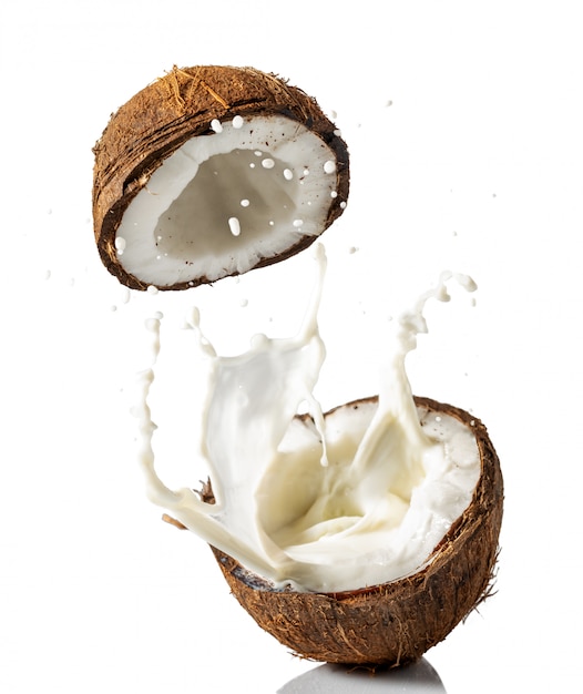 Photo broken coconut with a splash of milk on a white background