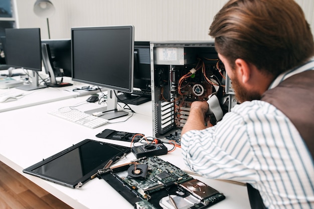 Broken computer disassembling, close-up. Repairman take apart CPU to find failure reason. Electronic repair, renovation concept