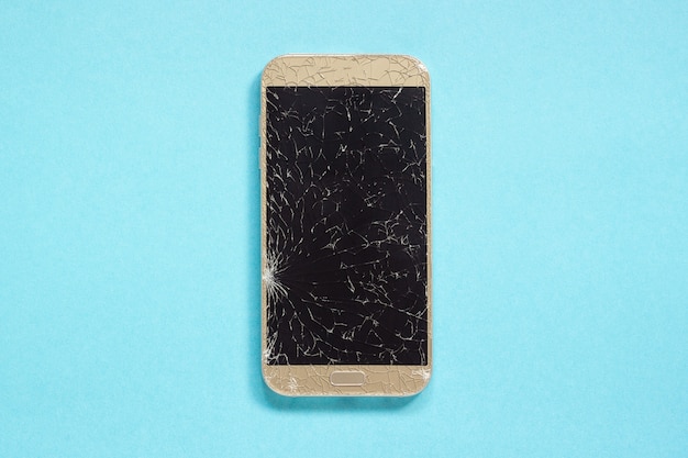 Фото Сломанные трещины сотовый телефон на синем фоне