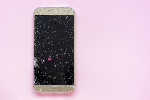 Broken cracks mobile phone and text OMG on pink background