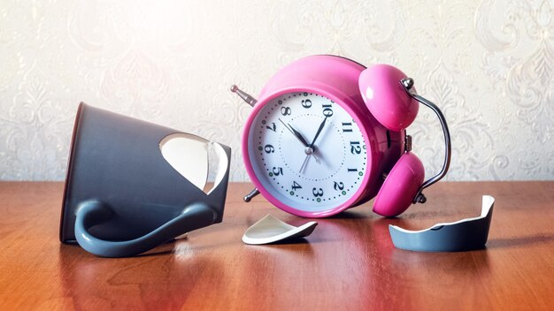 Broken cup and overturned clock on the desk in the office