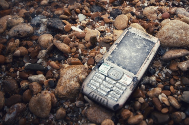 broken and drowned phone on stones in the sea