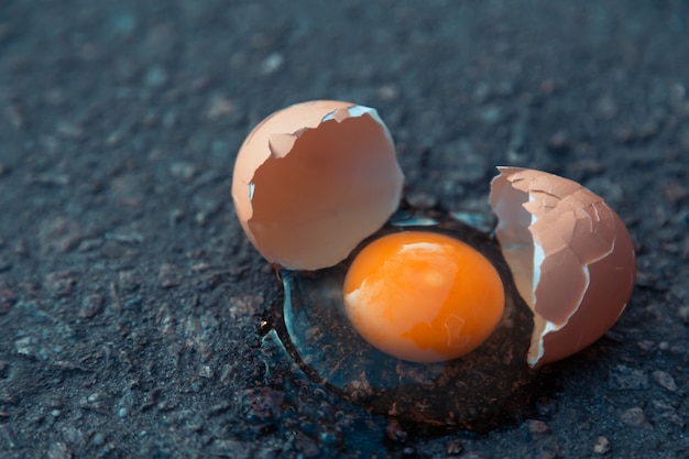 Broken egg on asphalt as a symbol of failure, negative experience, destruction, death.