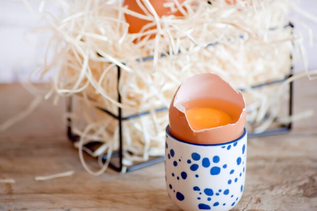A broken egg in a blue polka dot egg cup on a wooden table
