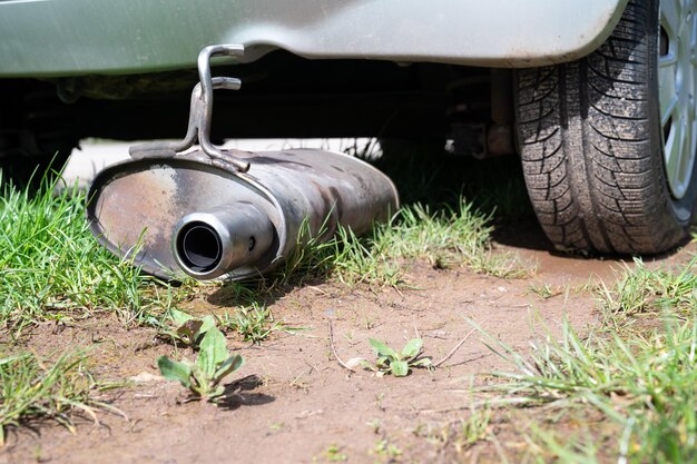 Foto scappamento rotto e silenziatore di un'auto silenziatore arrugginito caduto sulla strada guasto del veicolo