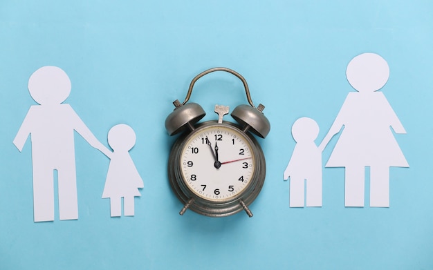 Photo broken family, divorce. split paper family, alarm clock on blue