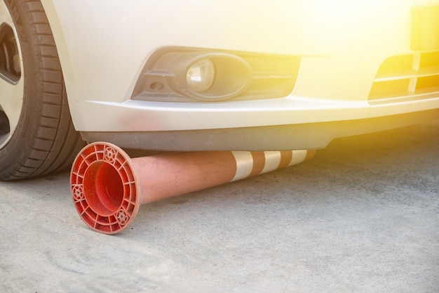 Broken flexible traffic bollard under the car on the road