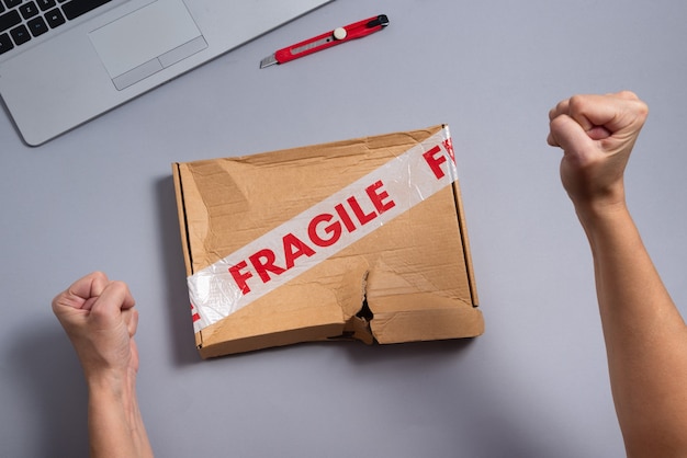 Broken fragile parcel, torn cardboard box on office desk