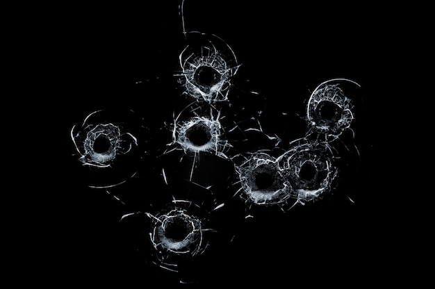 Broken glass multiple bullet holes in glass isolated on black