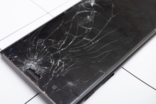 The broken glass screen of the smartphone lies on the tablet for repair