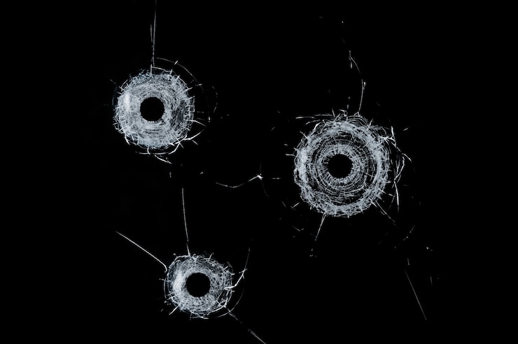 Photo broken glass triple bullet holes in glass isolated on black