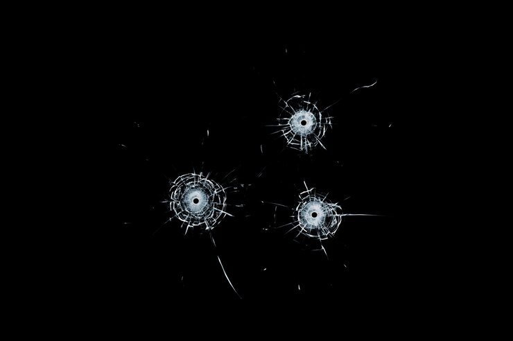 Photo broken glass triple bullet holes in glass isolated on black