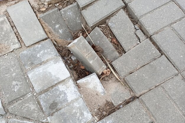 Broken gray tiles on the sidewalk closeup