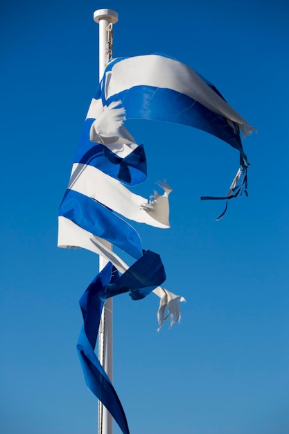 A broken greek flag with a clear blue sky