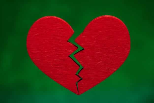 Broken heart. Crack in the red heart, Breaking the relationship. Green background.