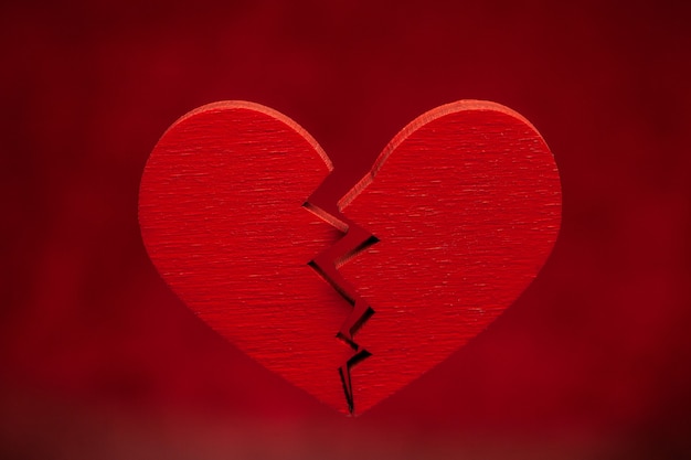 Broken heart. Crack in the red heart, Breaking the relationship. Red background.