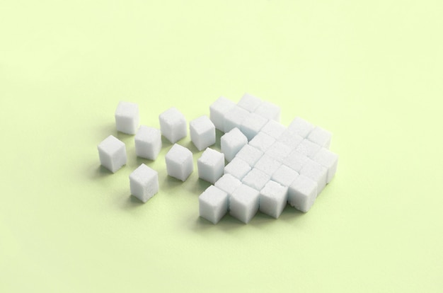 A broken heart made of sugar cubes lies on a trendy pastel lime