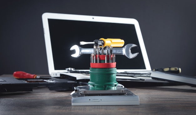 Broken laptop with a wrench and screwdriver on the table. Computer repair service