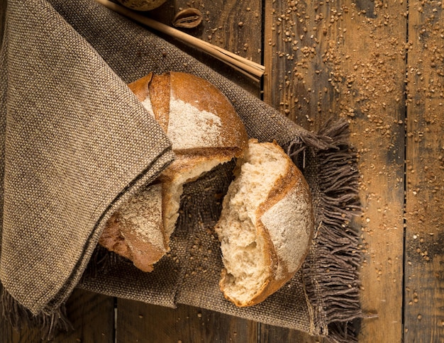 Разбитый буханка хлеба на тканевой салфетке и деревянных досках с крошками