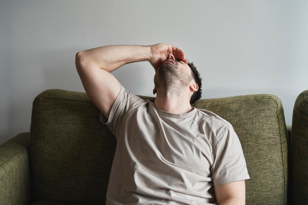 写真 家でソファに横たわっている壊れた男