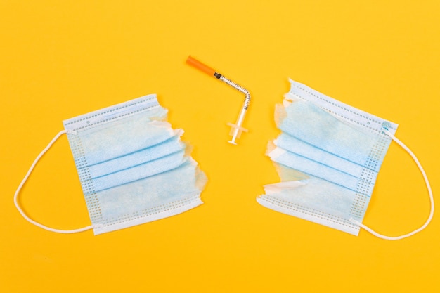 Broken medical syringe and torn medical face mask