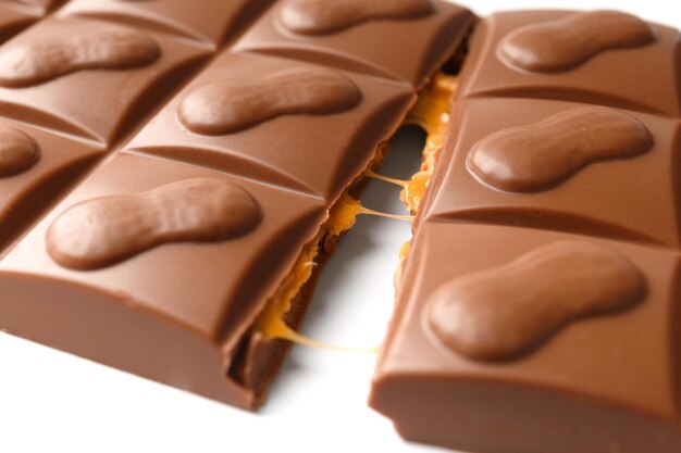 Broken milk chocolate bar with nuts on a white background close up