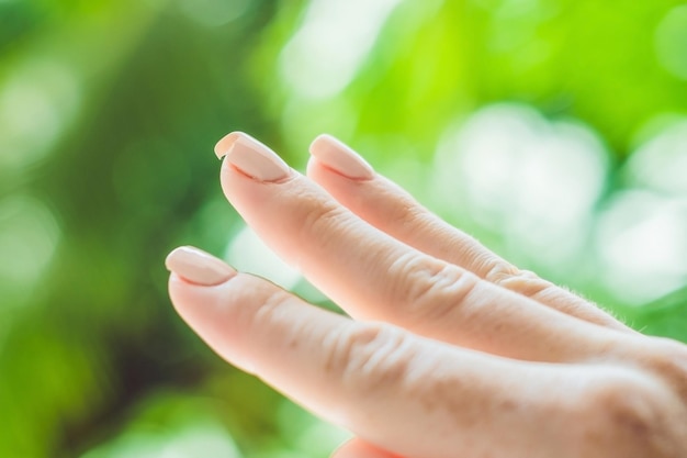 Broken nail on a woman's hand with a manicure on a green background