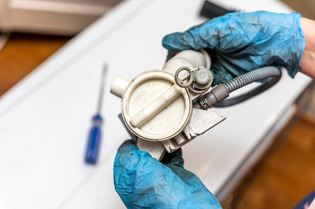 A broken old washing machine water pump in the hands of repairman